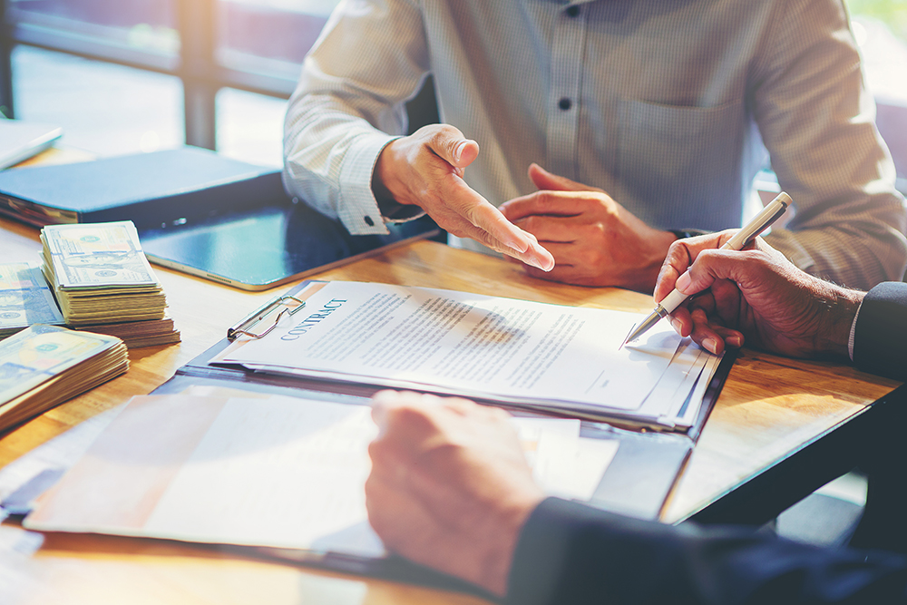 Businessman puts signature on contract at business meeting and p